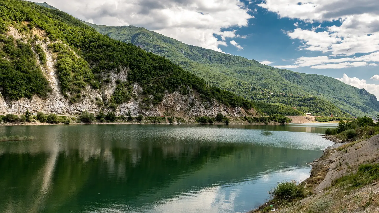 Тиркизните води на Дебарското Езеро опкружени со зелени и карпести планински падини