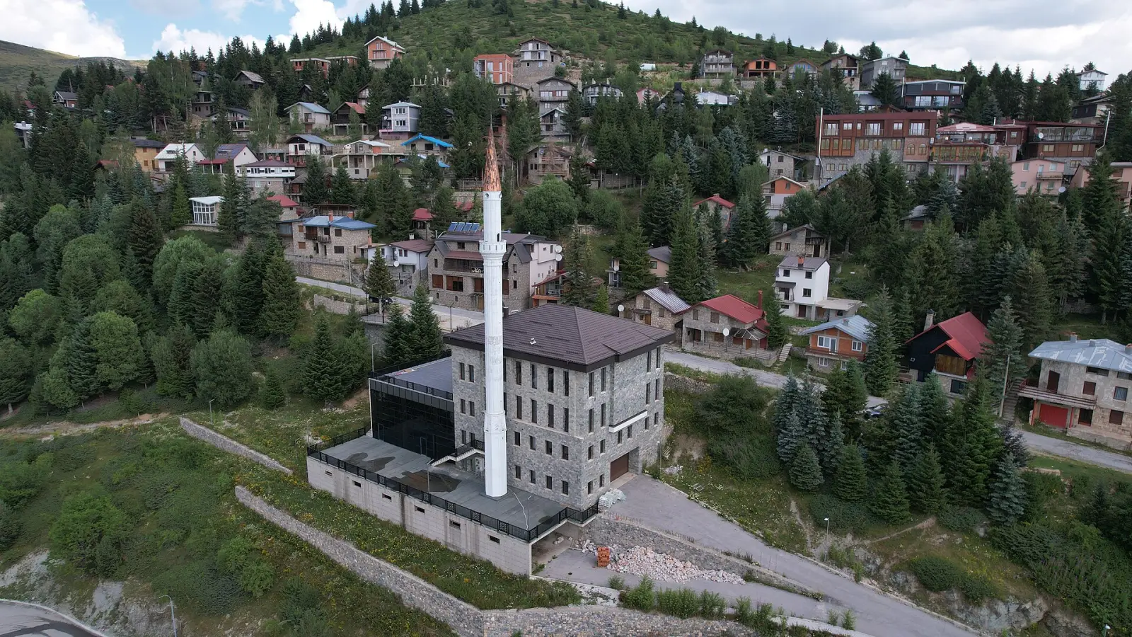 Џамијата во Попова Шапка, опкружена со куќи и борови на планинската падина