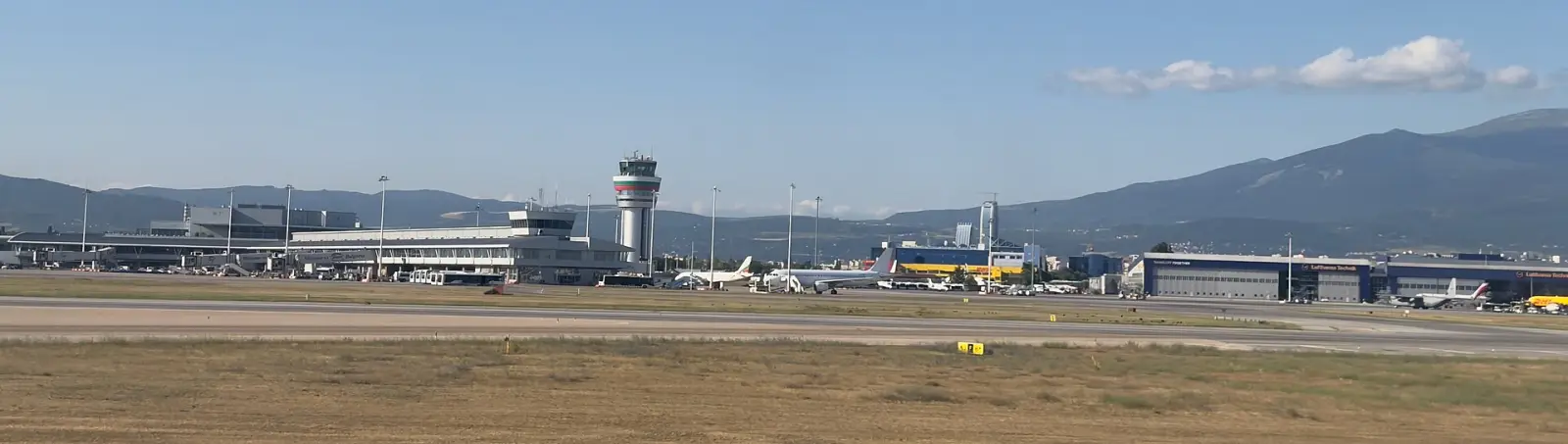 Кулата за контрола на летањето и терминалската зграда на аеродромот во Софија, со планината Витоша во позадина
